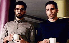 Two Men Standing Next To Each Other Holding Cups Of Coffee . GIF