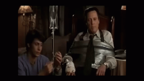 Two Men Standing Next To Each Other In A Dark Room GIF