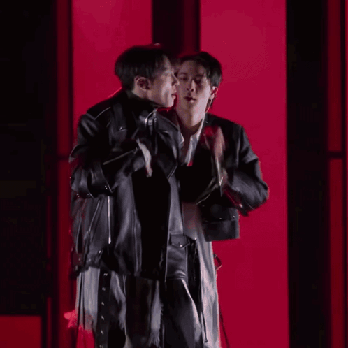 Two Men Standing Next To Each Other In A Dark Room GIF