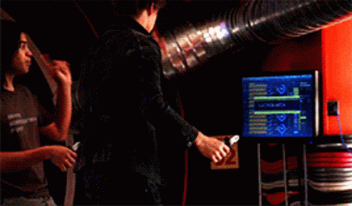 Two Men Standing Next To Each Other In A Room With A Blue Pipe In The Background GIF
