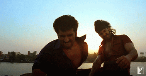 Two Men Standing Next To Each Other In Front Of A Sunset GIF