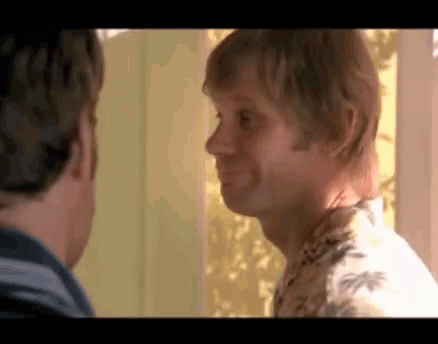 Two Men Standing Next To Each Other Looking At Each Other One In Hawaiian Shirt GIF