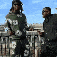 Two Men Standing Next To Each Other On A Balcony With One Wearing Sunglasses GIF