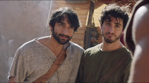 Two Men Standing Next to Each Other One in Gray Shirt