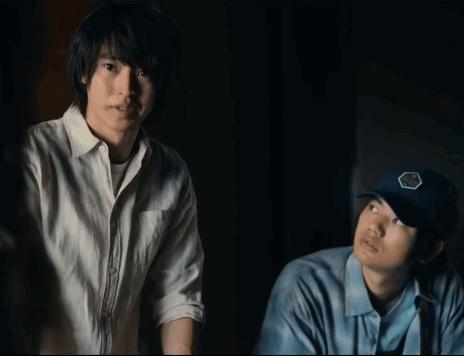 Two Men Standing Next To Each Other One Wearing A Blue Hat With A Badge On It GIF