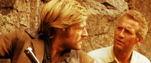 Two Men Standing Next To Each Other With One Holding A Sword GIF