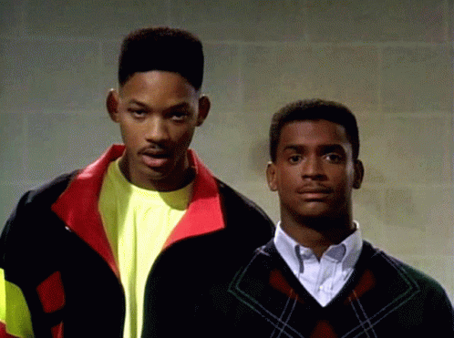 Two Men Standing Next To Each Other With One Wearing A Sweater GIF