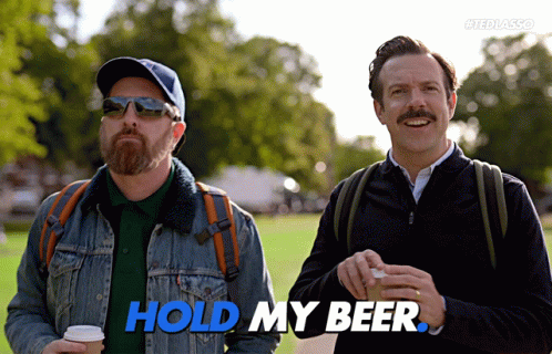 Two Men Standing Next To Each Other With The Words Hold My Beer In Blue GIF
