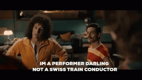 Two Men Standing Next To Each Other With The Words Im A Performer Darling Not A Swiss Train Conductor Written Below Them GIF