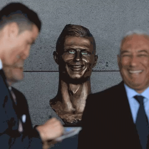 Two Men Standing Next to Man's Head Statue
