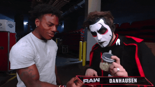 Two Men Standing Next to Raw Danhausen Sign