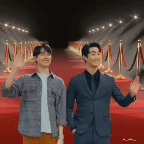 Two Men Standing on Red Carpet Waving