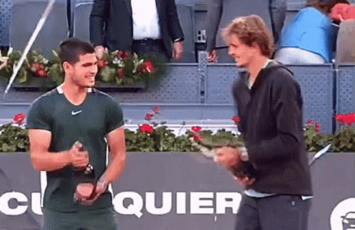 Two Men Standing On Tennis Court With Quier Sign GIF