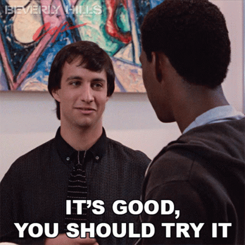 Two Men Standing One Saying It's Good You Should Try It