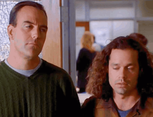 Two Men Standing One With Eyes Closed