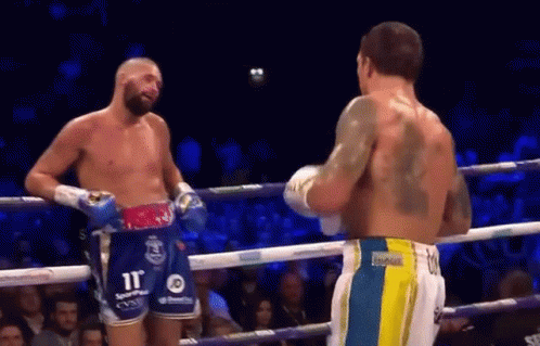 Two Men Talking in Boxing Ring, One With Back Tattoo
