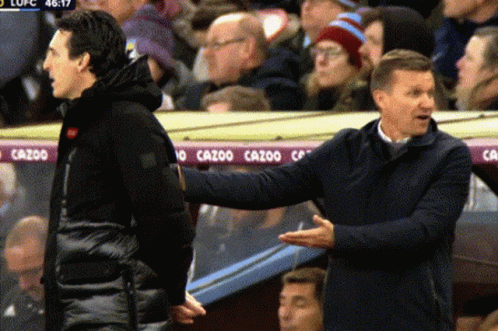 Two Men Talking In Front Of Cazoo Banner GIF