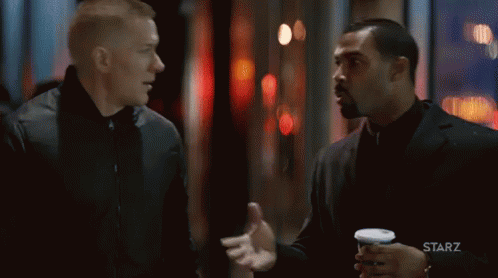Two Men Talking In Front Of Starz Logo GIF