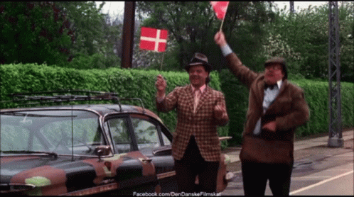 Two Men Waving Flags In Front Of A Camouflage Car With Facebook.com On The Bottom Right GIF