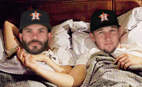Two Men Wearing Astros Hats Are Laying In Bed Together GIF
