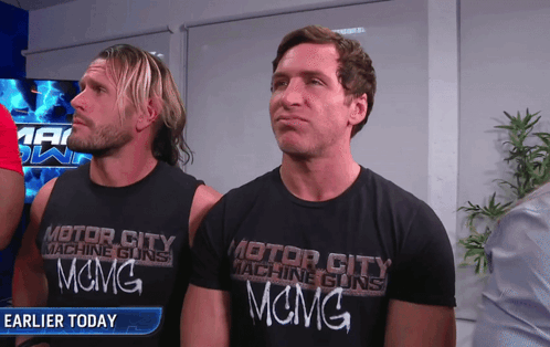 Two Men Wearing Black Motor City Machine Guns Shirts GIF