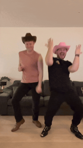 Two Men Wearing Cowboy Hats Are Dancing In Front Of A Couch GIF