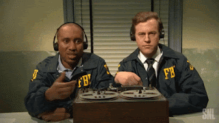 Two Men Wearing Fbi Uniforms Are Sitting At A Desk GIF