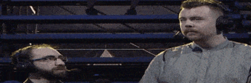 two men wearing headphones are standing next to each other in a stadium