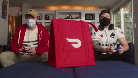 Two Men Wearing Masks Are Playing A Video Game With A Red Bag That Says Pioneer On It GIF