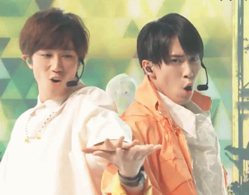 Two Men Wearing Microphones Are Standing Next To Each Other In Front Of A Green Background GIF