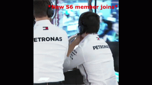 Two Men Wearing Petronas Shirts Are Looking At Something GIF