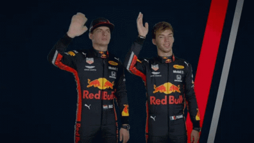 two men wearing red bull racing uniforms are waving