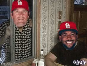 Two Men Wearing St Louis Cardinals Hats Are Looking Out Of A Window GIF