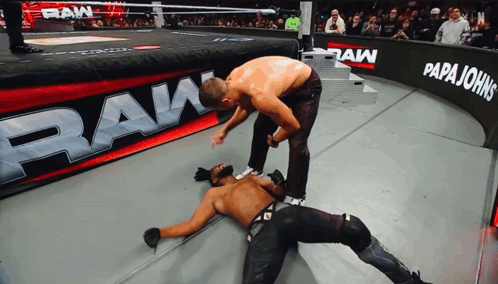 Two Men Wrestling in Front of Papa Johns Banner