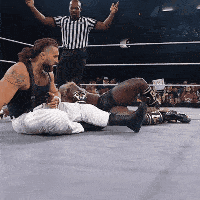 Two Men Wrestling in Ring, One on Floor