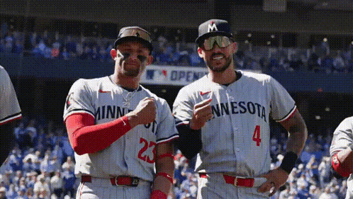 Two Minnesota Baseball Players Are Posing For A Picture On The Field GIF