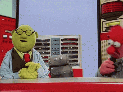 Two Muppets Are Sitting At A Table And One Is Wearing Glasses And A Tie GIF