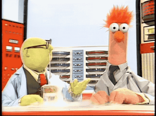 Two Muppets Are Sitting At A Table And One Of Them Is Wearing A Lab Coat GIF