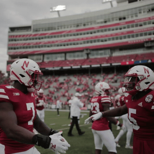 Two Nebraska Football Players Shake Hands in Front of Stadium