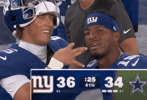 Two New York Giants Players Standing Next to Scoreboard