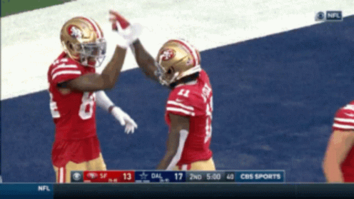 Two Nfl Players High Five Each Other On A Field GIF