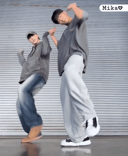 Two People Are Dancing In Front Of A Wall And The Word Mika Is On The Bottom GIF