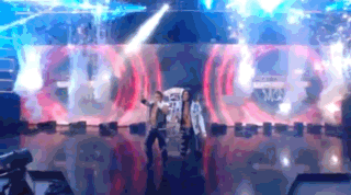 Two People Are Dancing On A Stage In Front Of A Large Screen That Says ' A ' On It . GIF