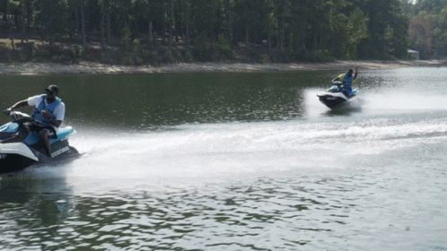 Two People Are Riding Jet Skis On A Lake And One Of The Jet Skis Has The Word Sea Doo On It GIF