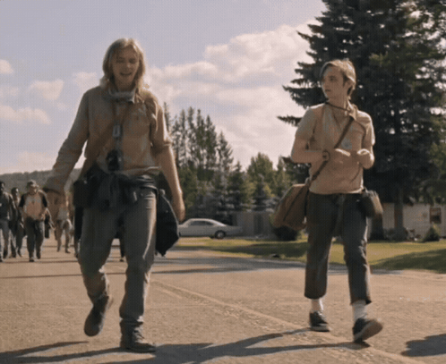 Two People Are Walking Down A Street And One Has A Purse Around Her Shoulder GIF