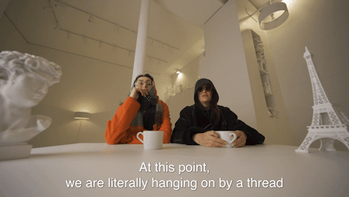 Two People At Table Hanging On By A Thread GIF