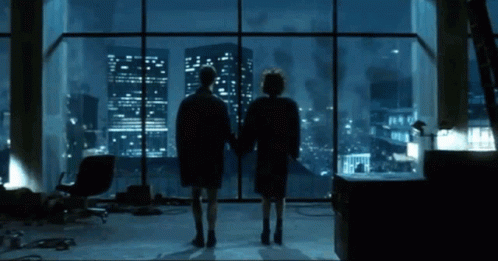 Two People at Window Overlooking City at Night