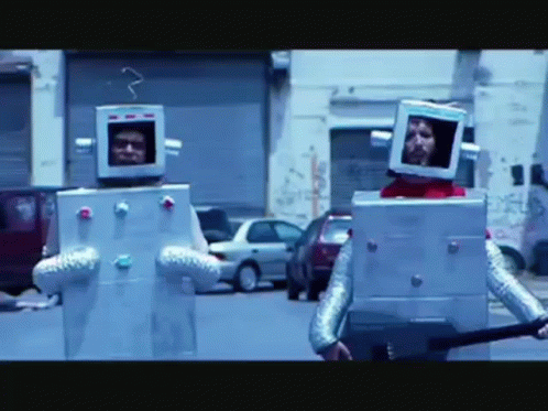 Two People Dressed As Robots Walking Down Street GIF