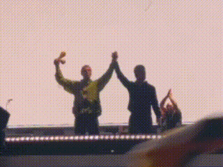 Two People High-Fiving on Stage in Front of Crowd