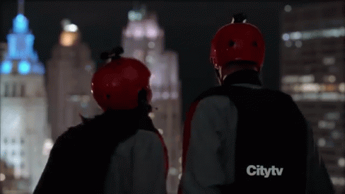 Two People in Red Helmets Watching City at Night